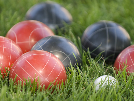 Red and black bocce balls scattered on lush grass at The Preserve Resort & Spa.