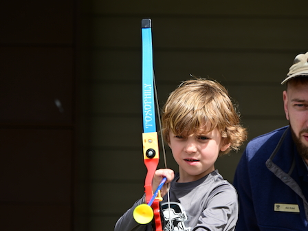 A young boy with a toy bow practices Nerf Archery, enjoying a playful activity at Preserve Resort & Spa.