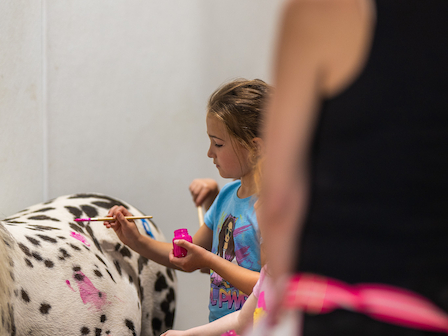 Young artist joyfully painting a pony at The Preserve Resort & Spa's Paint the Pony event, full of creativity and fun.