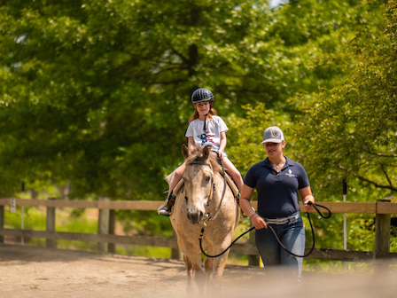 A young rider confidently practices riding at the Pegasus Kids Camp, guided by The Preserve Resort & Spa's expert equestrian staff.